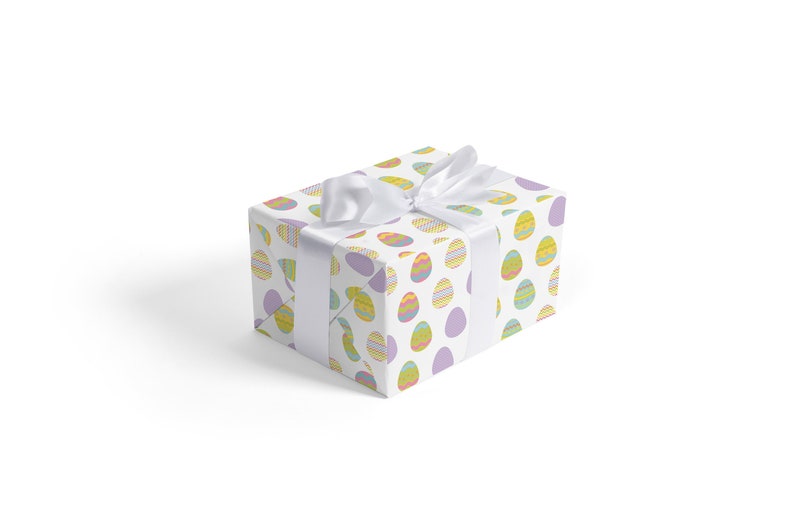 May include: A white gift box with a white satin ribbon tied in a bow. The box is wrapped in paper with a pattern of colorful Easter eggs.