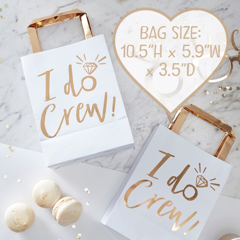 May include: Two white paper gift bags with gold handles and gold foil lettering that says "I do Crew!" and a diamond ring graphic. The bags are 10.5 inches high by 5.9 inches wide by 3.5 inches deep.