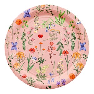 May include: A round, pink paper plate decorated with a floral pattern. The design features various colorful flowers and green foliage, including orange, yellow, blue, and red blooms. The plate has a slightly raised edge.