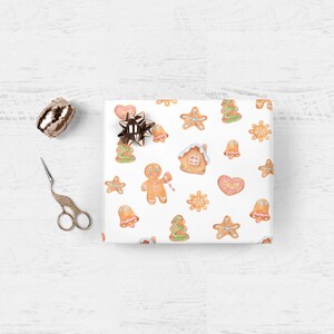 May include: White wrapping paper with a repeating pattern of gingerbread cookies. The cookies are in the shape of a gingerbread man, a house, a star, a bell, a snowflake, a heart, and a Christmas tree. The cookies are decorated with icing and sprinkles.