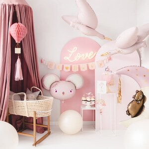May include: A pink baby shower scene with balloons, a crib, and decorative elements. The scene includes a large moon-shaped balloon, a mouse-shaped balloon, and stork balloons. A banner reads "Oh Baby".