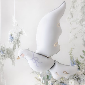 May include: A white dove balloon with a light blue bow and gold accents. The balloon is surrounded by white and blue flowers.