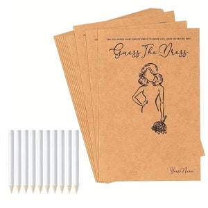 May include: A stack of rectangular tan paper cards featuring the black printed text Guess The Dress, a line drawing of a person holding a bouquet, and the text Your Name, accompanied by ten plain white pencils with unsharpened wooden tips.