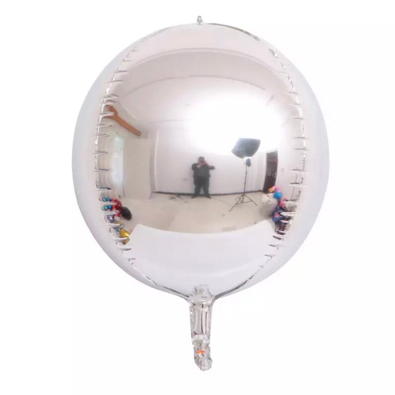 Może przedstawiać: Duży, okrągły, srebrny balon z odblaskową powierzchnią. Balon jest napompowany i ma długi, cienki ogon.