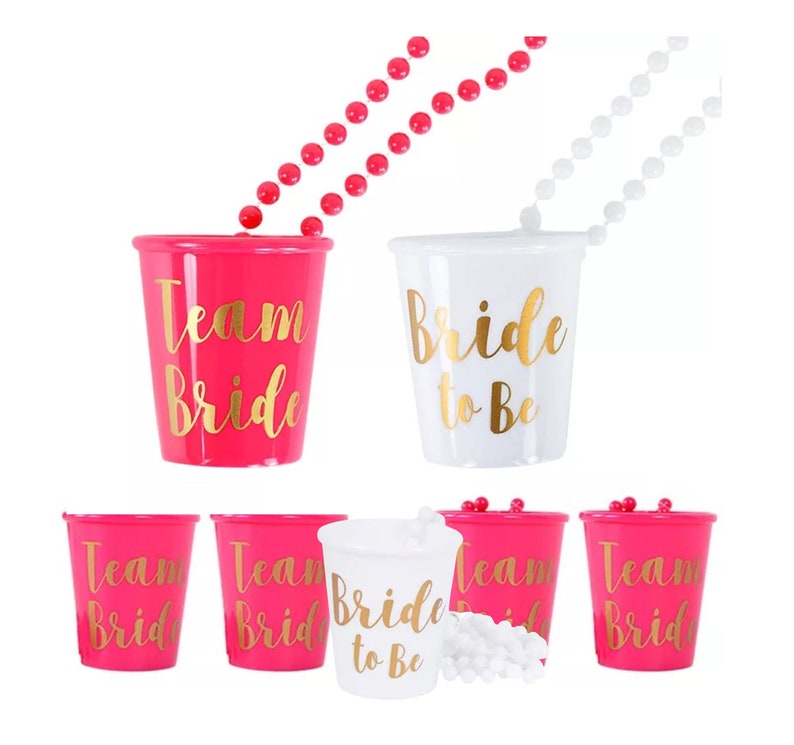 Pu&ograve; includere: Set di bicchieri da shot in plastica rosa e bianca con scritta dorata. I bicchieri recitano "Team Bride" e "Bride to Be". Il set include due collane con perline rosa e bianche.