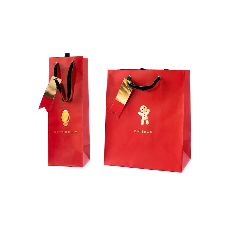 May include: Two red gift bags with gold accents and green handles. One bag features a gold lightbulb graphic and the text "GETTING LIT." The other bag has a gold gingerbread man graphic and the text "OH SNAP."