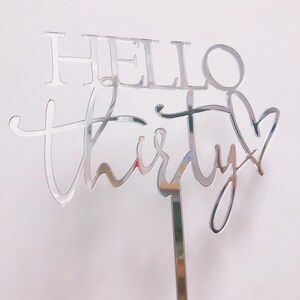 以下が含まれることがあります： 「Hello Thirty」というテキストが書かれた、銀色の鏡面アクリル製のケーキトッパー。30の数字は、最後にハートの形をしています。