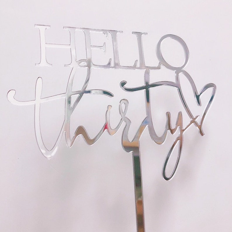 以下が含まれることがあります： 「Hello Thirty」というテキストが書かれた、銀色の鏡面アクリル製のケーキトッパー。30の数字は、最後にハートの形をしています。
