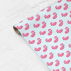 May include: Pink flamingo pool floats on a light blue background. The pattern repeats throughout the wrapping paper.