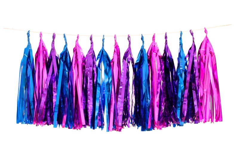 Pode incluir: Uma guirlanda de borlas coloridas para festas em tons de azul, roxo e rosa. As borlas s&atilde;o feitas de material brilhante e met&aacute;lico e est&atilde;o penduradas em um fio fino contra um fundo branco. Ideal para decora&ccedil;&otilde;es de festas.