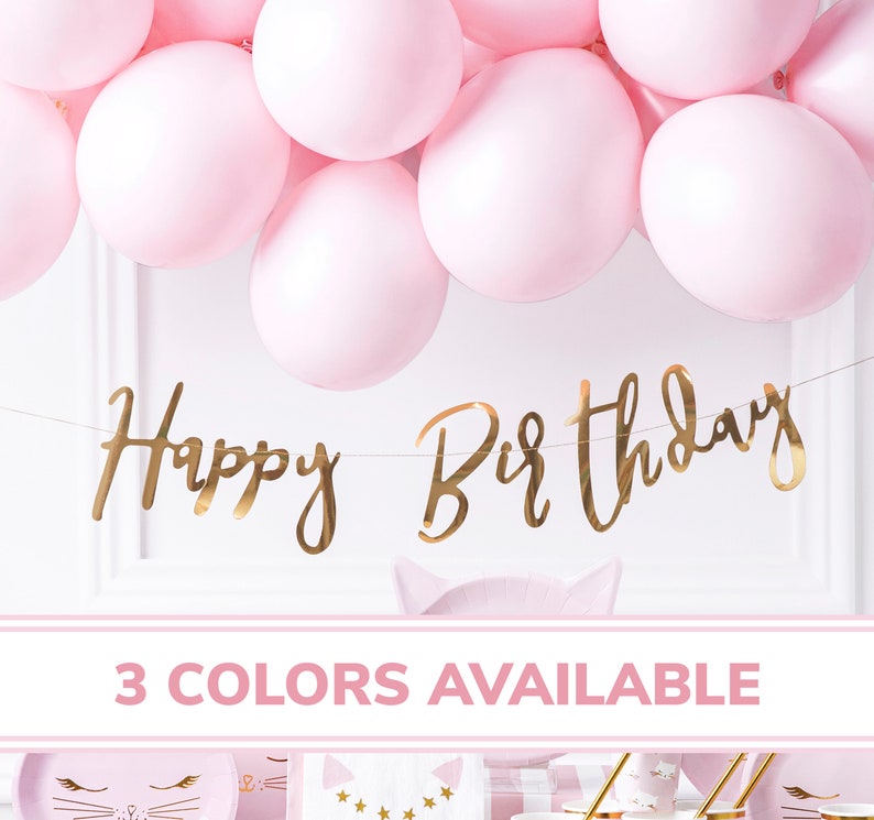 May include: Gold foil Happy Birthday banner with pink balloons in the background. The banner is strung on a clear string. The text "3 COLORS AVAILABLE" is at the bottom of the image.