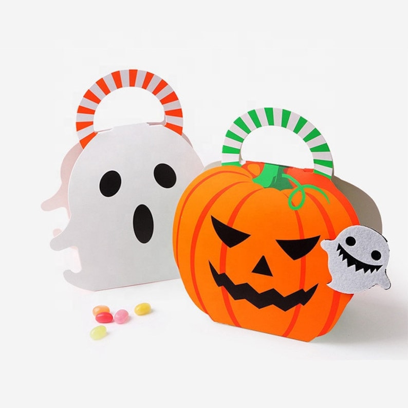 May include: Two Halloween treat bags made of cardstock. One bag is white and shaped like a ghost with a black face and an orange and white striped handle. The other is orange and shaped like a pumpkin with a black face and a green striped handle.