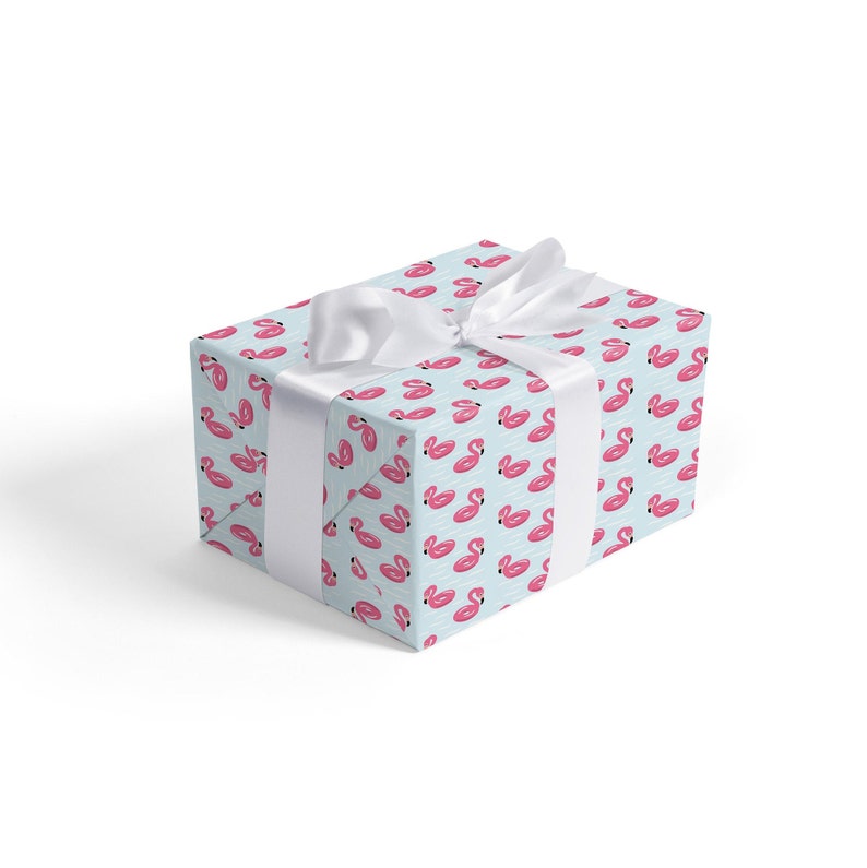 May include: A light blue gift box with a white ribbon. The box is wrapped in paper with a repeating pattern of pink inflatable flamingo pool floats.