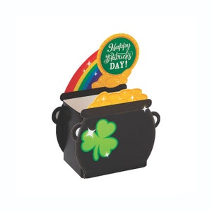 Puede incluir: Una olla negra de oro con un arcoíris y un trébol. La olla tiene un letrero que dice "¡Feliz día de San Patricio!"