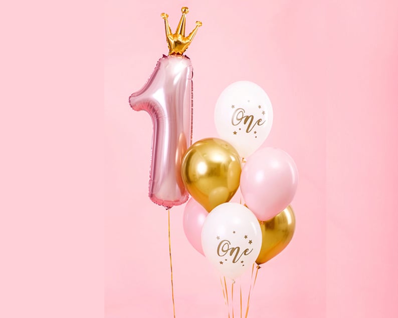 Pu&ograve; includere: Un palloncino rosa a forma di numero uno con una corona dorata in cima, circondato da palloncini dorati, bianchi e rosa con la scritta "One" stampata su di essi.