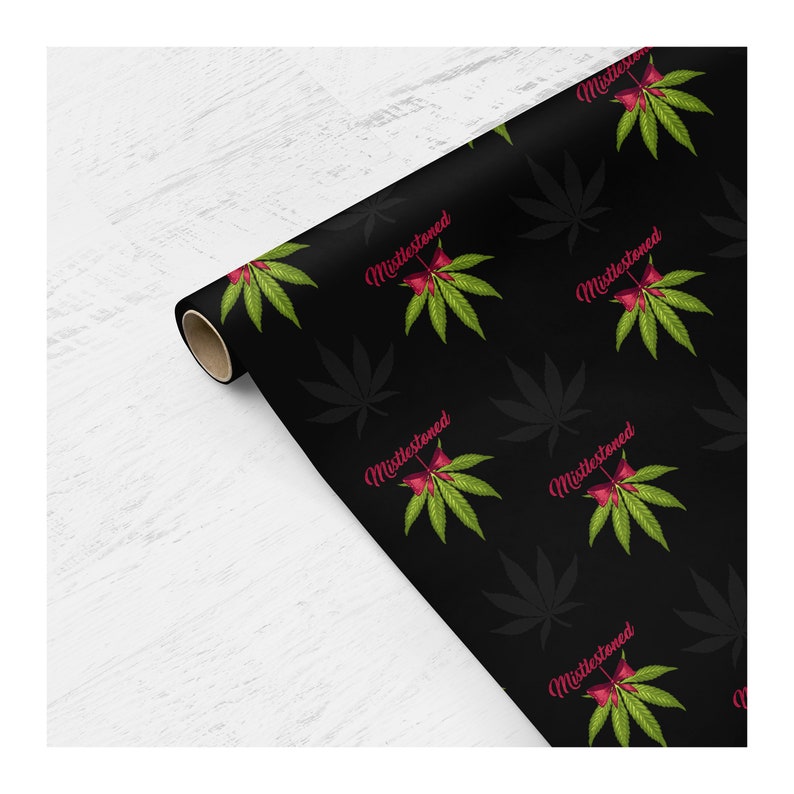 May include: Black wrapping paper with a repeating pattern of green marijuana leaves and red mistletoe with the text "Mistlestoned" in pink.