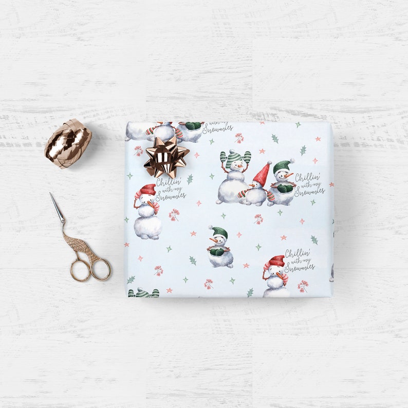 May include: A blue and white wrapping paper with a snowman pattern. The paper features a repeating pattern of snowmen with the text "Chillin' with my snowmen".