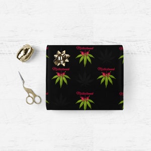May include: Black wrapping paper with a repeating pattern of green marijuana leaves and red bows with the text "Mistlestoned" in pink.