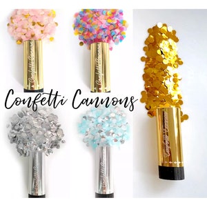 May include: Confetti cannons with gold, silver, blue, pink and rainbow confetti. The cannons are gold with the words "Confetti Cannon" printed on them.