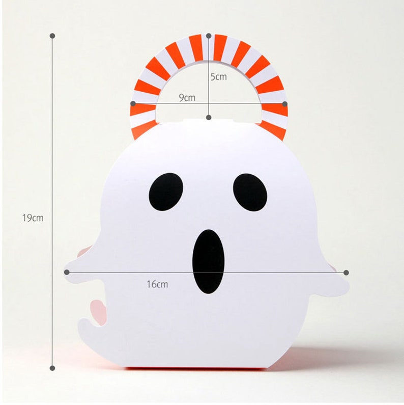 May include: A white ghost-shaped paper treat box with a black oval mouth and two black oval eyes. The box features an orange and white striped arched handle. Dimensions are marked as 19 cm total height, 16 cm width, 9 cm handle width, and 5 cm handle height.
