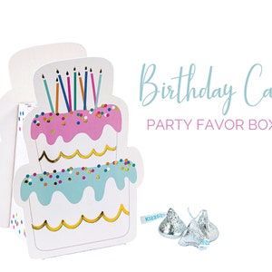 May include: White cardboard party favor boxes shaped like a two-tier birthday cake with pink and blue frosting, colorful sprinkles, and candles. The text "Birthday Cake Party Favor Boxes" is printed in blue.