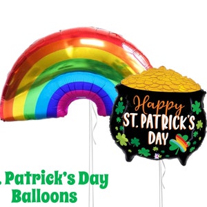May include: Two St. Patrick's Day themed foil balloons. One is a rainbow arch and the other is a black pot of gold with the text "Happy St. Patrick's Day".