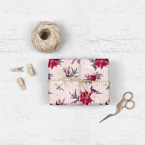 Pode incluir: Papel de embrulho listrado rosa e branco com um padr&atilde;o floral de poins&eacute;tia vermelha. O presente est&aacute; amarrado com barbante e um la&ccedil;o vermelho.