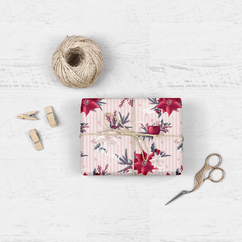 Pode incluir: Papel de embrulho listrado rosa e branco com um padr&atilde;o floral de poins&eacute;tia vermelha. O presente est&aacute; amarrado com barbante e um la&ccedil;o vermelho.
