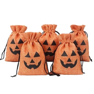 May include: A set of five orange burlap drawstring bags, each featuring a black printed jack-o'-lantern face. The bags have a textured fabric weave and are cinched at the top with thin black cords, creating a gathered opening for each pouch.