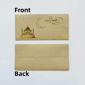 May include: Tan envelope with gold foil mosque, crescent moon, and floral designs. The front of the envelope has the Arabic text "Eid Mubarak". The back of the envelope is plain tan.