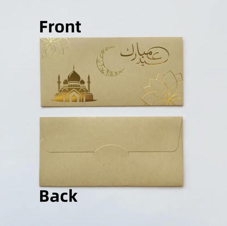 May include: Tan envelope with gold foil mosque, crescent moon, and floral designs. The front of the envelope has the Arabic text "Eid Mubarak". The back of the envelope is plain tan.