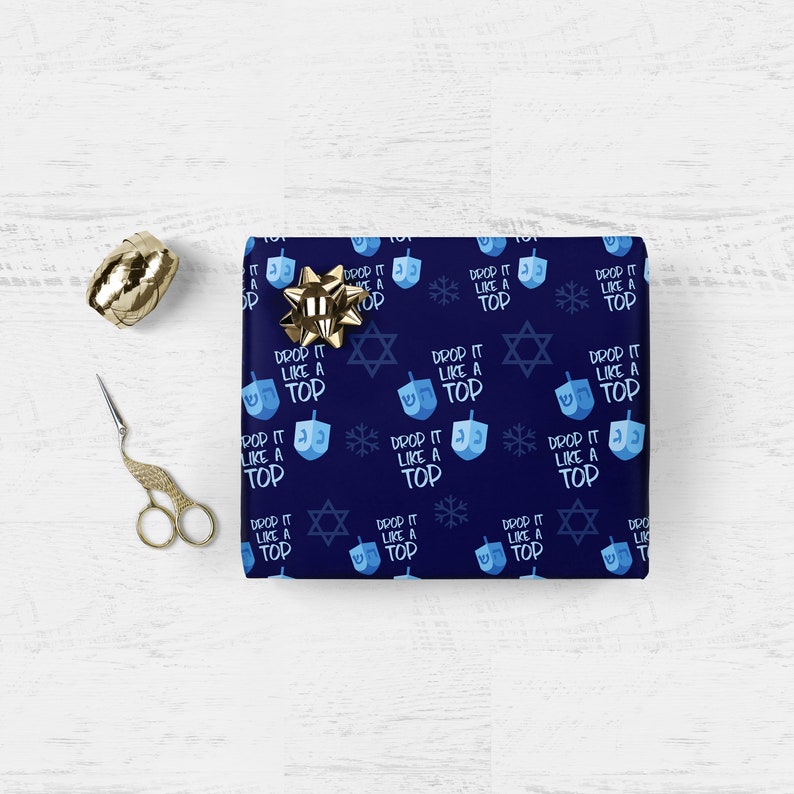 May include: Blue wrapping paper with a repeating pattern of blue dreidels, gold stars, snowflakes, and the text "Drop it like a top".