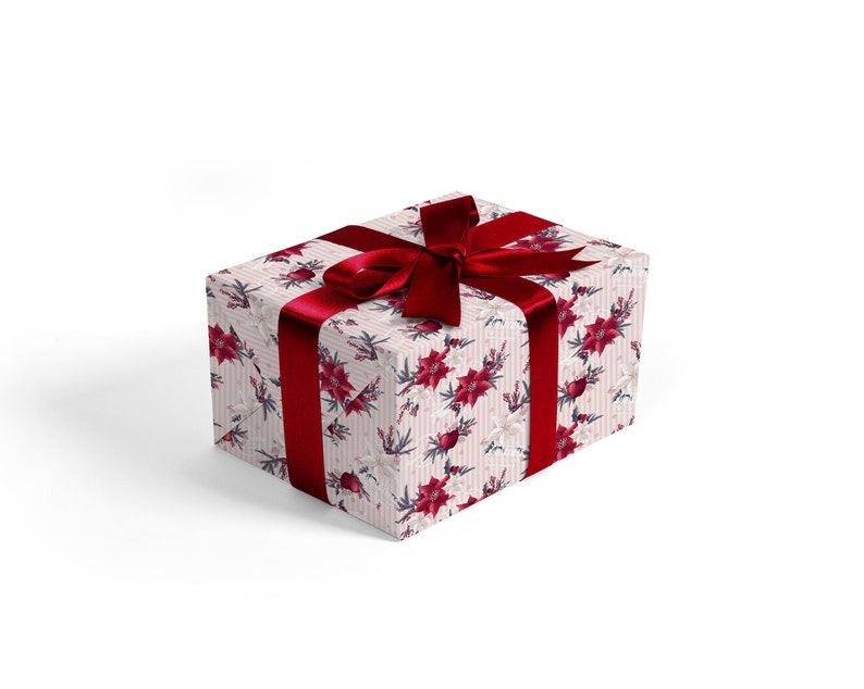 Pode incluir: Uma caixa de presente branca com uma fita vermelha e um padr&atilde;o floral de poins&eacute;tias vermelhas e flores brancas. A caixa est&aacute; embrulhada em papel de Natal festivo.