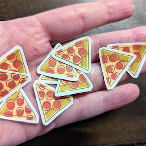 May include: A collection of eight pizza slice stickers with a white background, yellow crust, red pepperoni, and a light brown cheese topping.