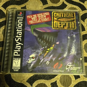 May include: A PlayStation game case for "Critical Depth" featuring a deep sea scene with a large shark-like creature. The game case has the PlayStation logo and the ESRB rating. The text "From the developers who know vehicular combat!" is also visible.