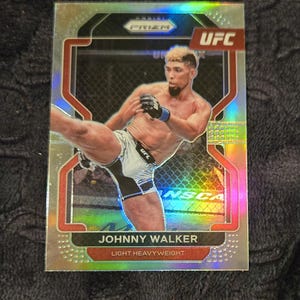 May include: A Panini Prizm UFC trading card featuring Johnny Walker in action. The card has a silver holographic background with red and black accents. The text "JOHNNY WALKER" and "LIGHT HEAVYWEIGHT" are displayed at the bottom.