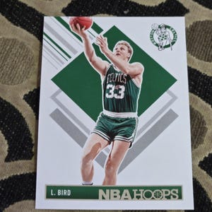 May include: Basketball trading card featuring Larry Bird of the Boston Celtics in a shooting pose. The card has a green and white design with the Celtics logo and the text "NBA Hoops."