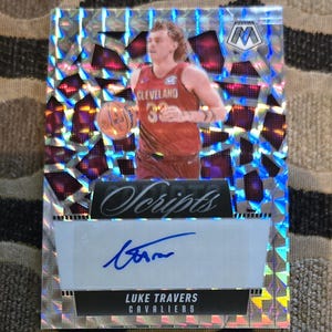 May include: A basketball trading card featuring Luke Travers of the Cleveland Cavaliers. The card has a mosaic design with a player image, an autograph, and the word "Scripts". The card is predominantly silver, red, and blue.