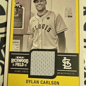 May include: A baseball card featuring a baseball player wearing a white and gray baseball uniform with the word "ST. LOUIS" on the front. The card has a yellow border and the text "MLB at Rickwood Field" and "Game-Used Memorabilia".