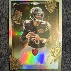 May include: A Topps Chrome football trading card featuring Caleb Williams of the Chicago Bears. The card has a holographic finish with decorative playing card suit symbols and the word "FORTUNE". The player is wearing a black and orange uniform.