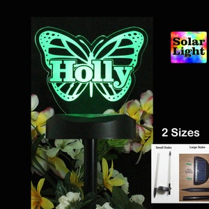 May include: A green solar powered butterfly garden stake with the name "Holly" on it. The stake is available in two sizes, small and large.