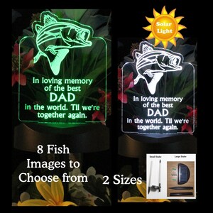 Pode incluir: Uma luz solar verde e branca com um design de peixe e o texto "Em mem&oacute;ria amorosa do melhor PAPAI do mundo. At&eacute; que nos reencontremos." A luz est&aacute; em uma estaca e h&aacute; dois tamanhos dispon&iacute;veis.