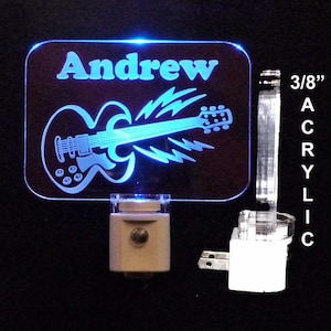 May include: A personalized night light with a blue LED light. The light features a white silhouette of an electric guitar with the name "Andrew" above it. The light is made of 3/8 inch acrylic.
