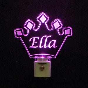 May include: A pink LED night light shaped like a crown with the name "Ella" inscribed in the center.