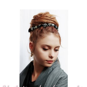 Puede incluir: Una mujer con largas rastas marrones peinadas en un moño con una scrunchie de tela con estampado blanco y negro.