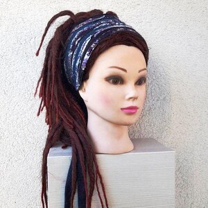 May include: A blue and purple patterned headband with a white background. The headband is worn on a mannequin with long, dark red dreadlocks.