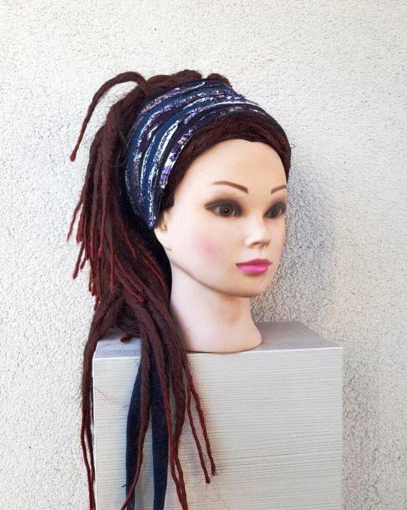 May include: A blue and purple patterned headband with a white background. The headband is worn on a mannequin with long, dark red dreadlocks.