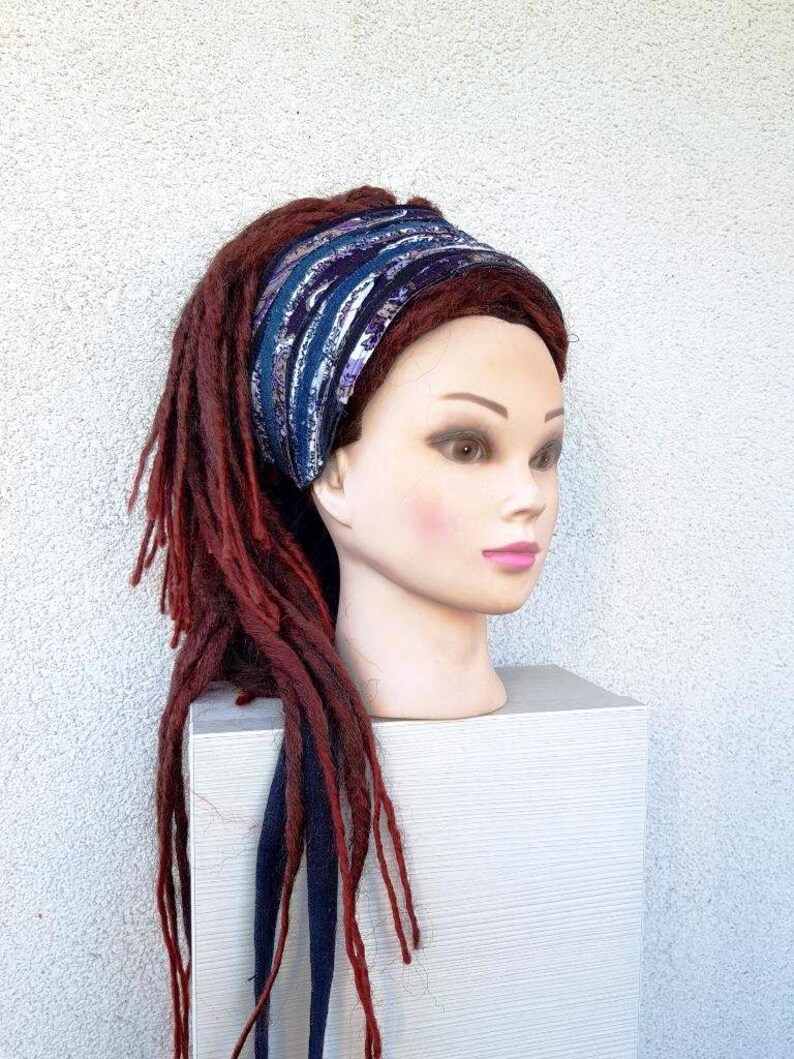 May include: A blue and purple patterned headband with a white background. The headband is worn on a mannequin with long, red dreadlocks.