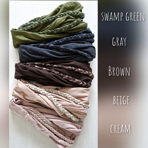 May include: A stack of five fabric headbands in swamp green, gray, brown, beige, and cream. Each headband features a braided fabric detail across the front. The colors are labeled on the right side as SWAMP GREEN, GRAY, BROWN, BEIGE, and CREAM.