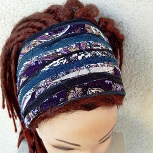 May include: A purple and blue patterned headband made from fabric scraps. The headband is worn on a mannequin with red hair.